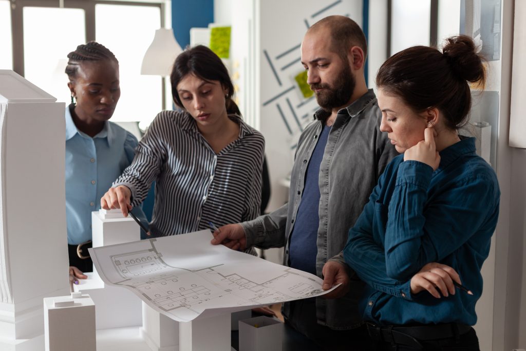 team multi ethnic architects designing blueprint plan scaled