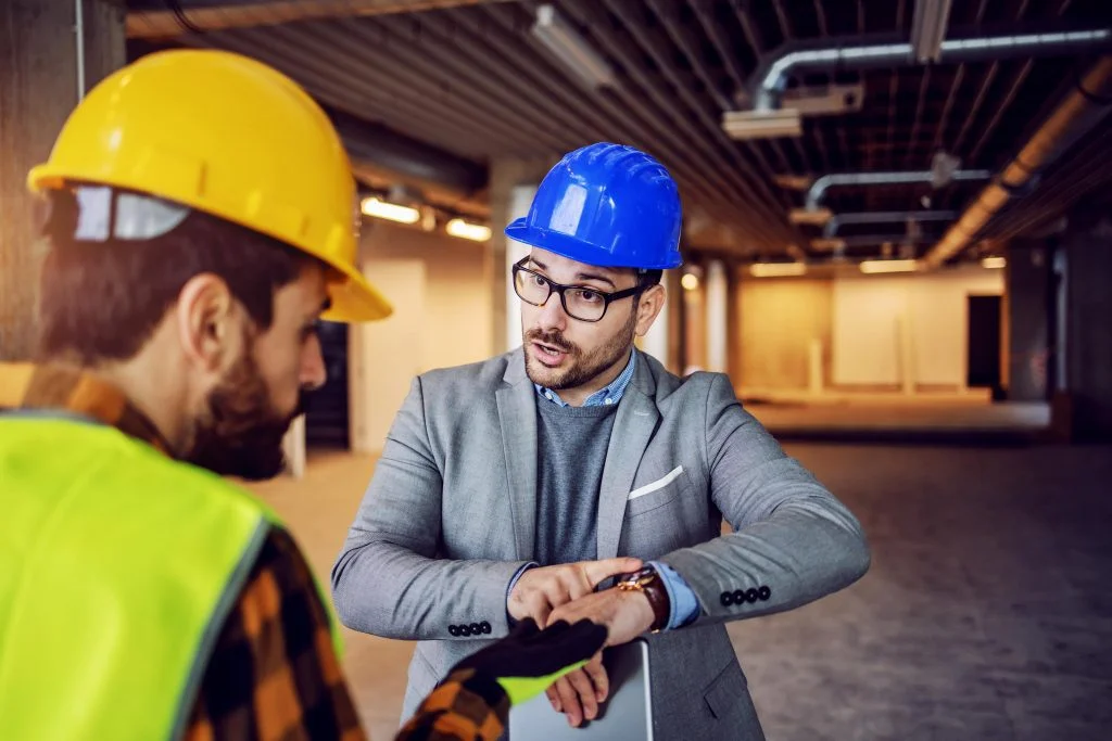 serious nervous supervisor arguing with his worker pointing wristwatch work must be done time with no excuses building construction process interior min scaled